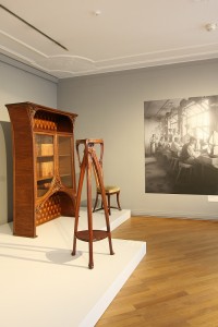 A Sellette, flower stand by Emile André, 1901, a cupboard by Louis Majorelle, 1900/05 and a photo of workers inside the Émile Gallé workshop, Nancy, as seen at Germany versus France. The Struggle over Style 1900-1930, Bröhan Museum Berlin