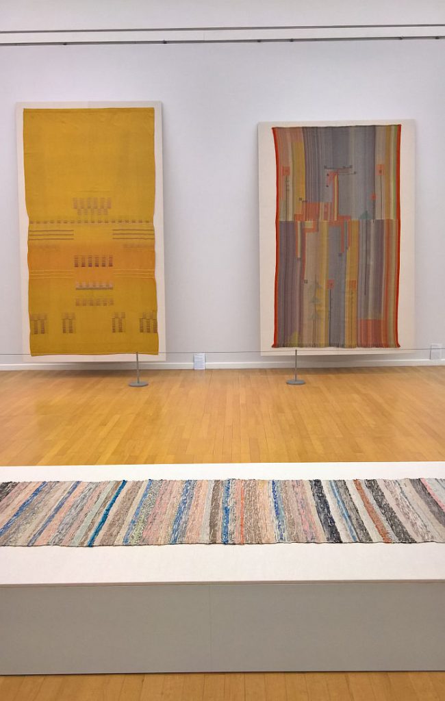 Two works by Else Mögelin (back) and a rag rug by Helene Schmidt-Nonné (foreground), as seen at Bauhaus. Textiles and Graphics, Kunstsammlungen Chemnitz