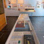 A view across items related to Le Corbsuier's cooperation with Salubra and towards a model of his and Pierre Jeanneret’s semi-detached house for the 1927 Weissenhofsiedlung building exhibition in Stuttgart, as seen at Le Corbusier and Color at the Museum für Gestaltung, Pavillon Le Corbusier, Zürich