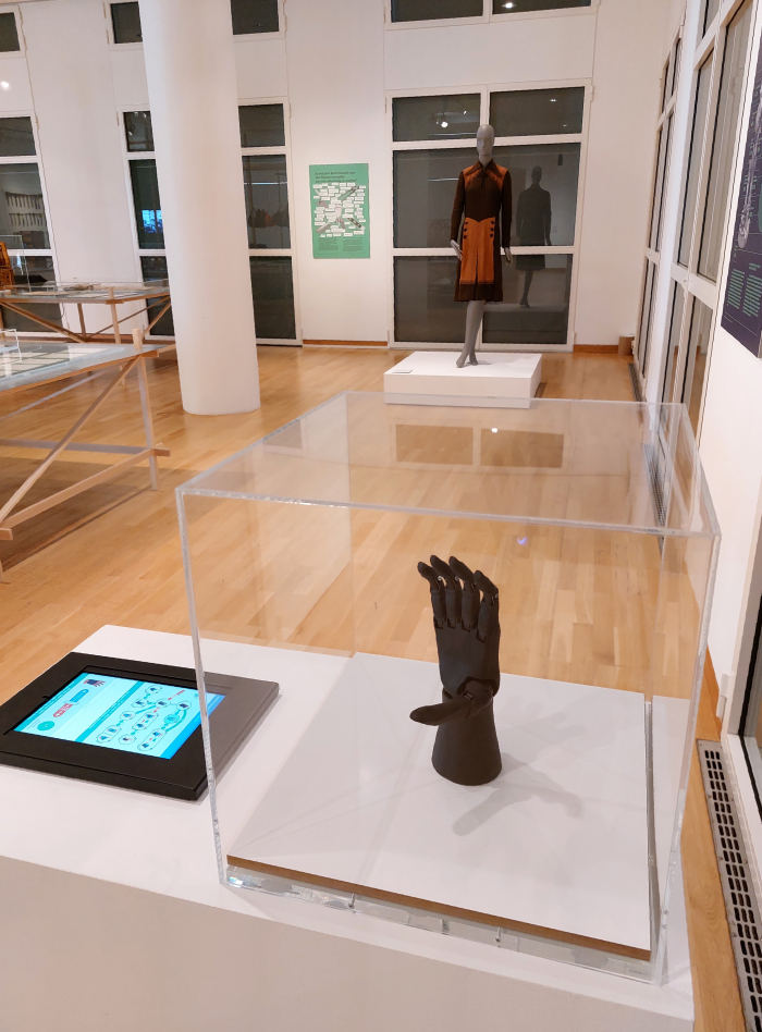 Vincent Systems’ computer controlled prosthetic hand (2020) greets Margarethe Zimmer Meisterstück wool dress (1948), as seen at Craft as Myth. Between Ideal and Real Life, Museum Angewandte Kunst, Frankfurt